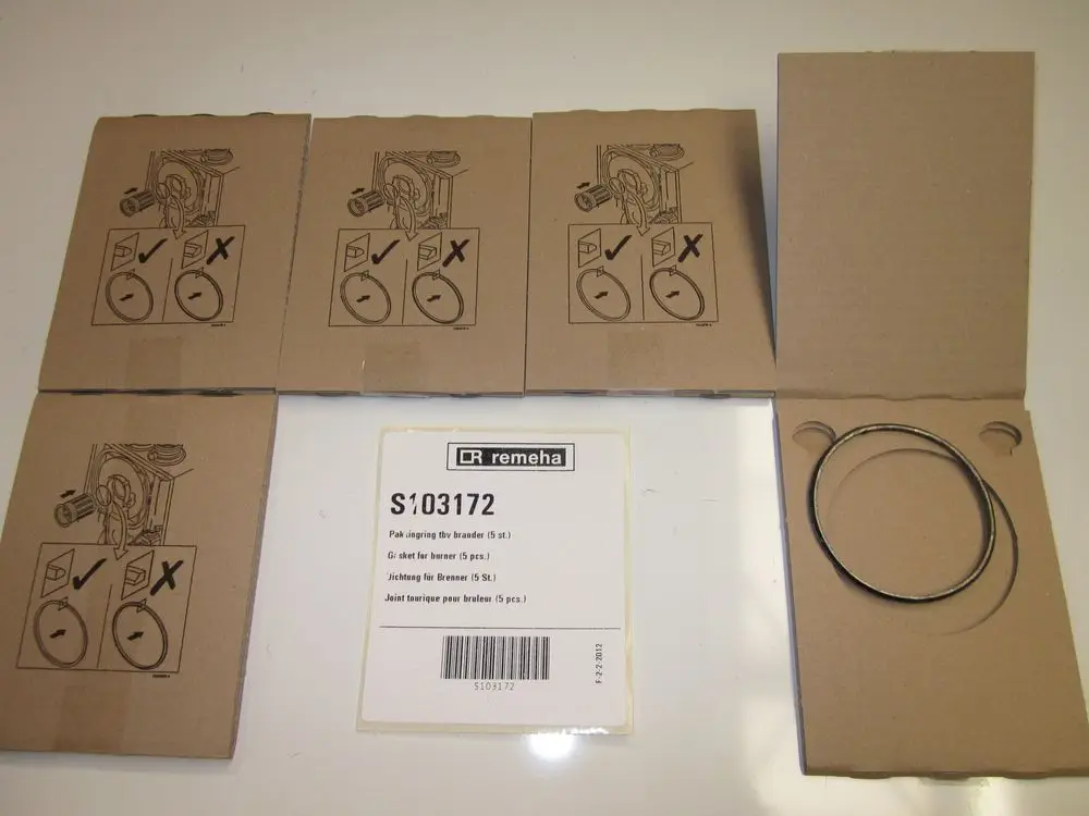 Mehrere Verpackungen mit Dichtungen für Brenner in Karton. Markenlabel "Remeha" sichtbar. Zeigt Montageanleitungen und Hinweise.